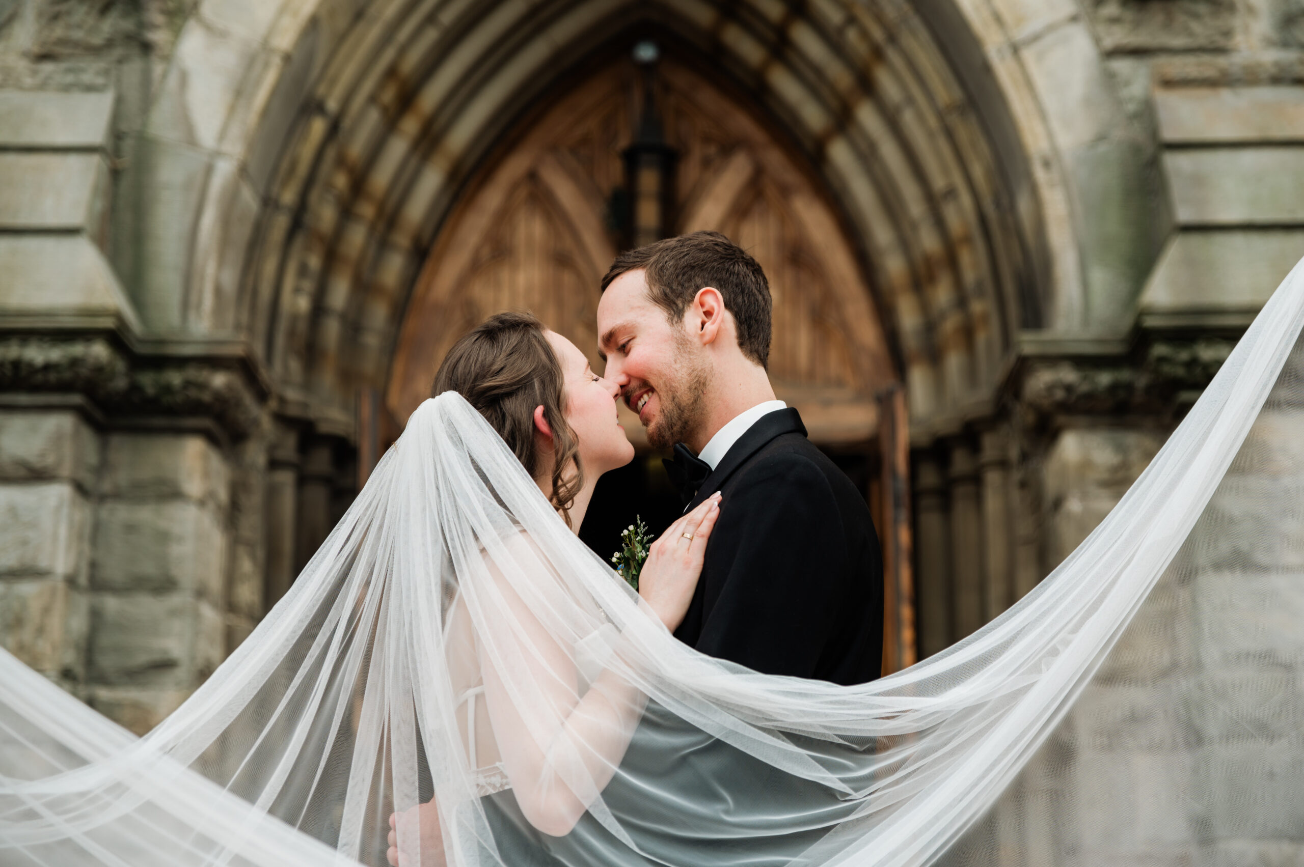 Bride and Groom sharing a kiss just outside of a catholic church just after exciting their ceremony.