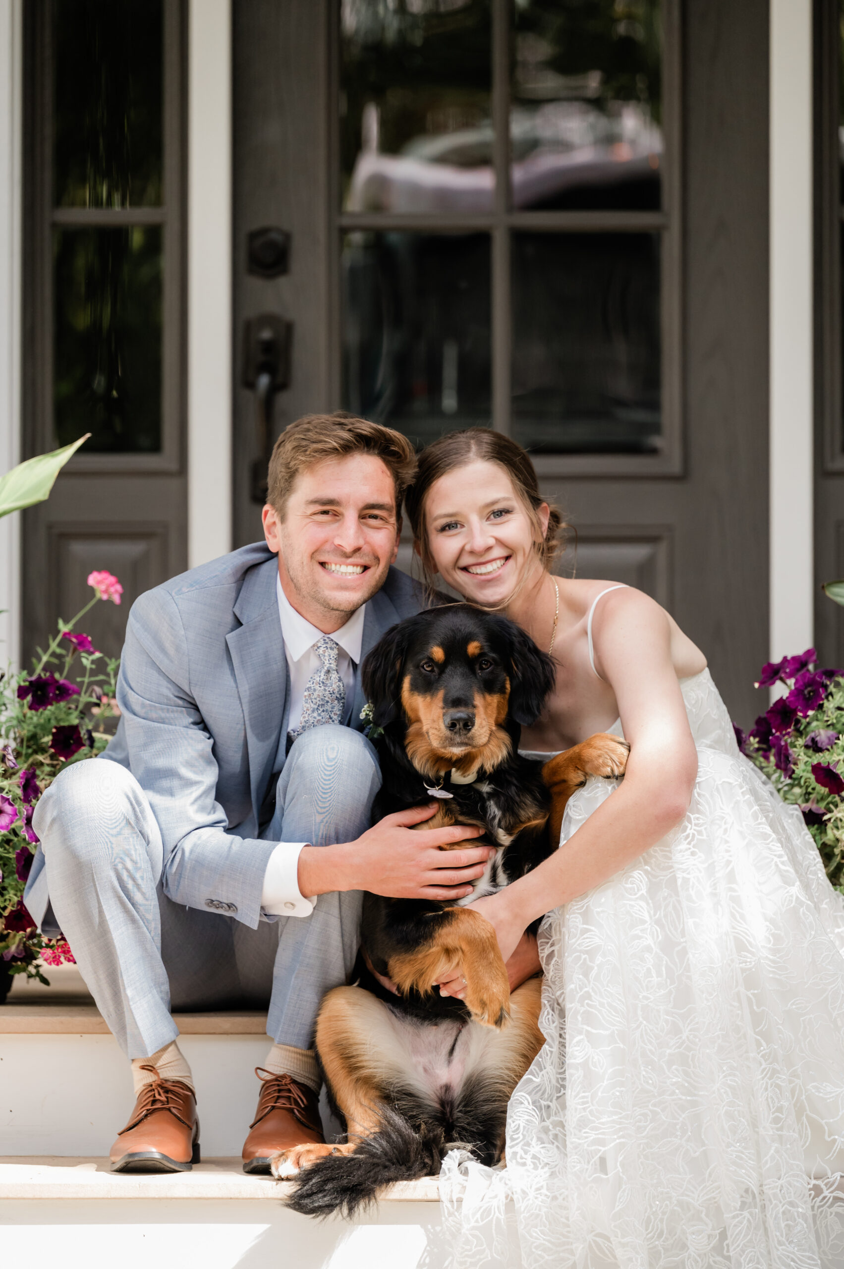 Smiling couple with dog on porch steps.