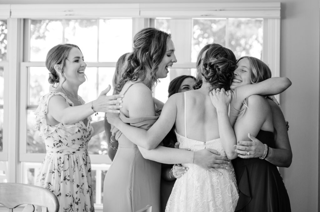 Group of women hugging and smiling indoors.