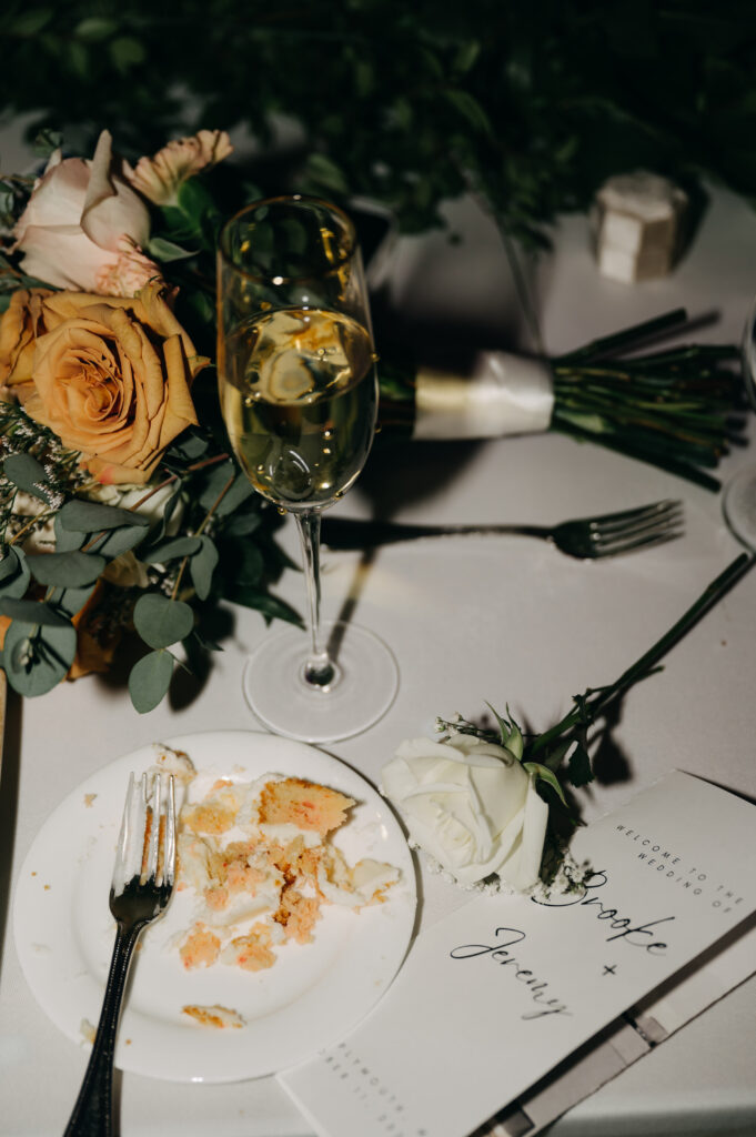 Wedding reception table with flowers and cake remnants.