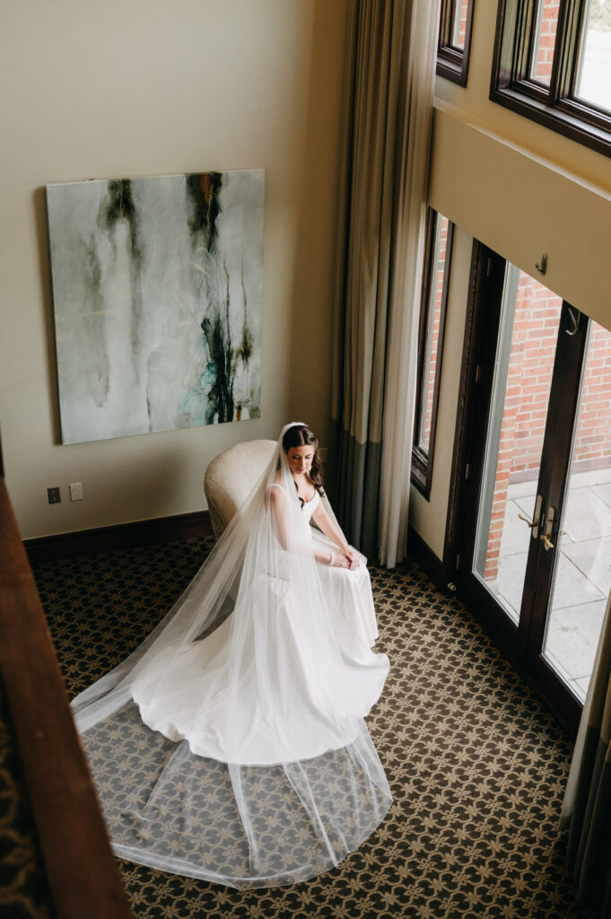 Bride in wedding dress sitting by window