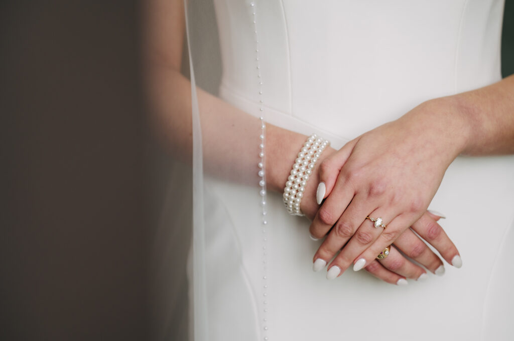 Bride's hands with pearl bracelet and ring.