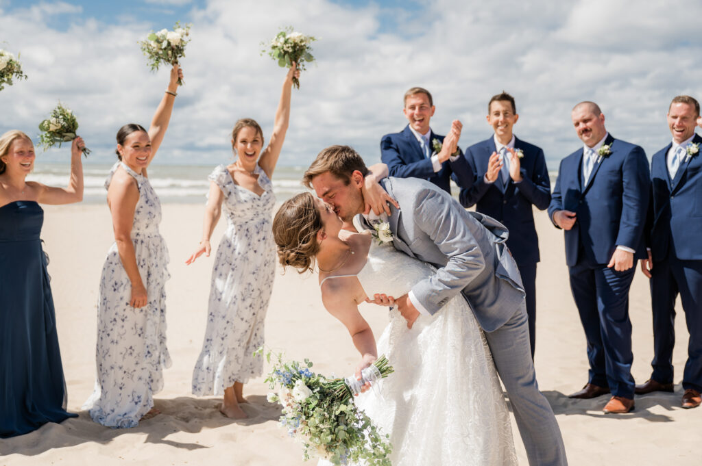 Beach wedding kiss with bridal party cheering.